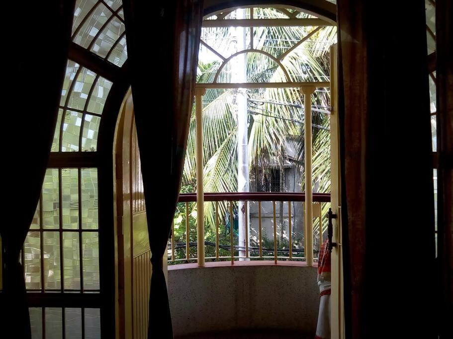 una ventana abierta con vistas a una palmera en Premium Apartment, Kolkata Airport en kolkata