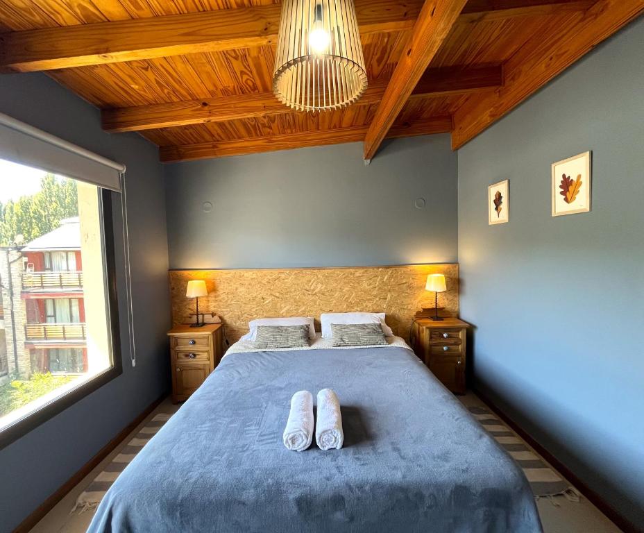 Un dormitorio con una cama con dos pares de zapatos. en Departamento Andes BIancos, luminoso y con excelentes vistas en SMA! en San Martín de los Andes