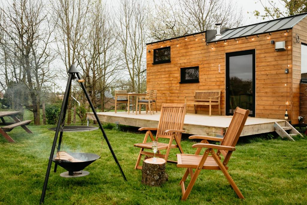 a small wooden cabin with chairs and a grill at Berta Tiny house in Verlaine