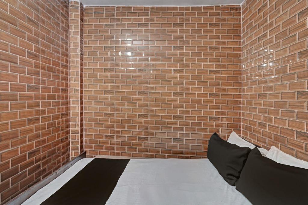 a brick wall with a bed in a room at SPOT ON Sunil Hotel & Restaurant in Sūrajpur