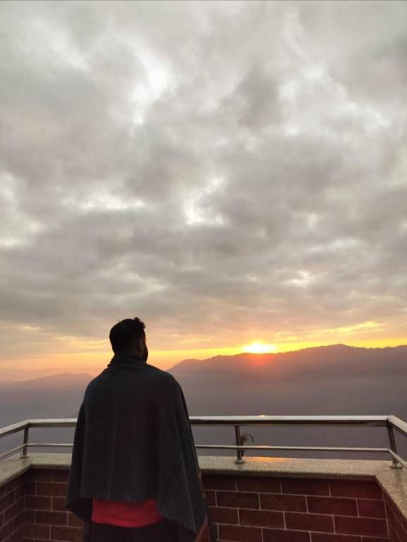 a man standing on top of a building looking at the sunset at Paul's stay in Darjeeling
