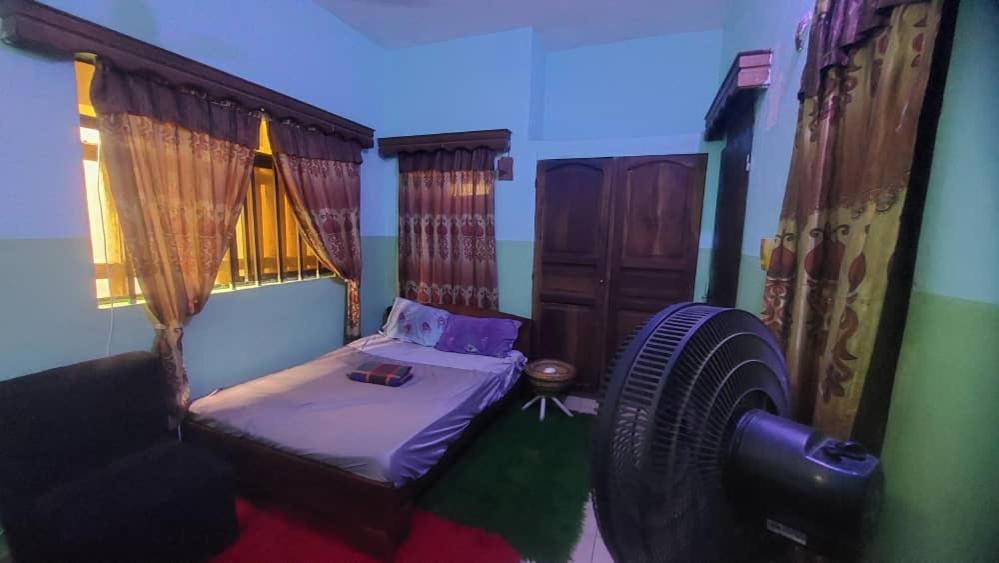 a small room with a bed and a fan at NEW LIGHT in Cotonou