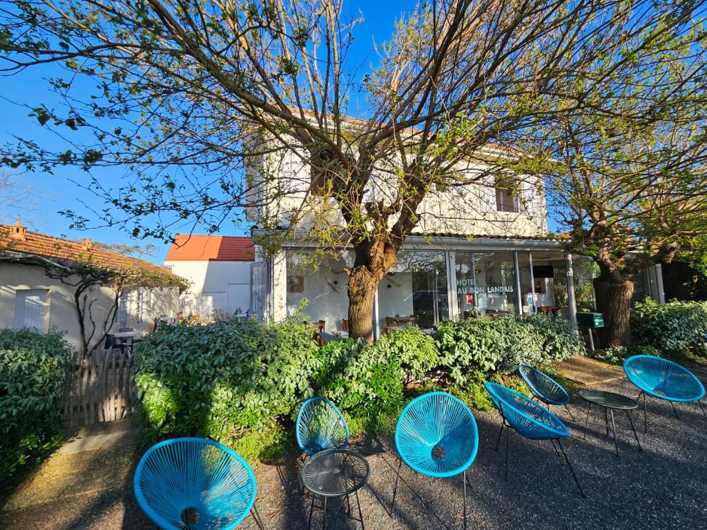 a group of blue tables and chairs in front of a house at Hôtel Au Bon Landais in Biscarrosse-Plage