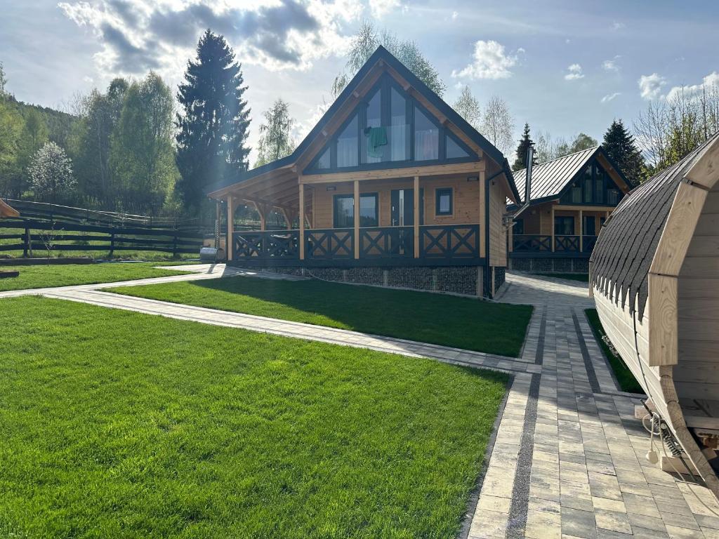 a large wooden house with a grass yard at Osada Wichrowe Wzgórze in Rajcza