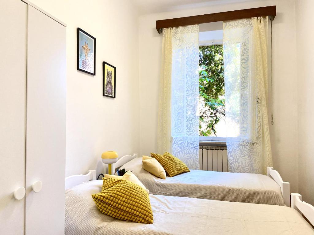 two beds in a room with a window at Casa Ganza in Pisa