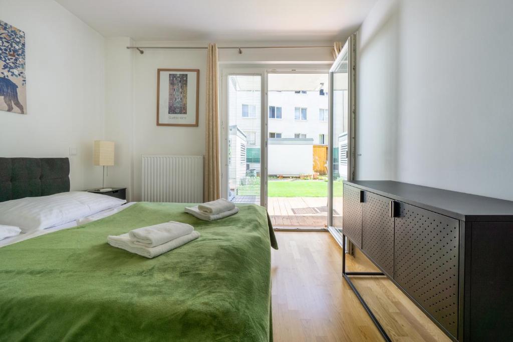 Apartment with garden close to Stadthalle, Westbahnhof في فيينا: غرفة نوم بسرير وبطانية خضراء