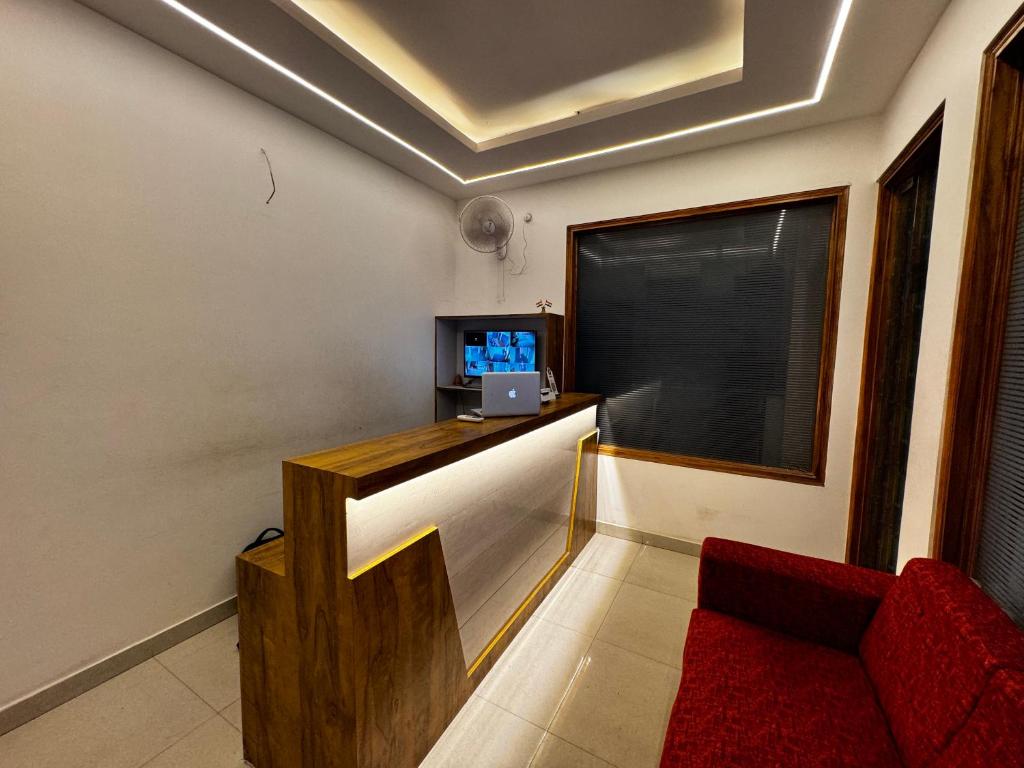 Hotel Daharm في لاكناو: غرفة معيشة بها أريكة حمراء وتلفزيون