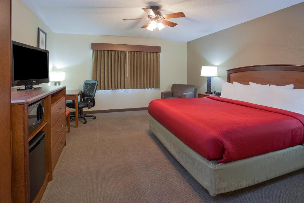 um quarto de hotel com uma cama e uma televisão de ecrã plano em AmericInn by Wyndham Roseau em Roseau
