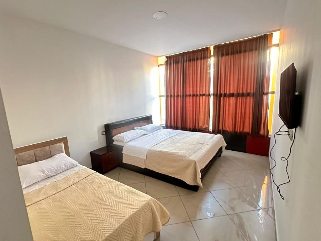 a bedroom with two beds and a flat screen tv at Hotel Kristali in Peshkopi