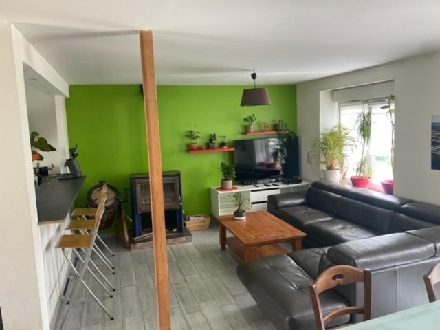 a living room with a black couch and a green wall at Maison avec jardin in Crozon