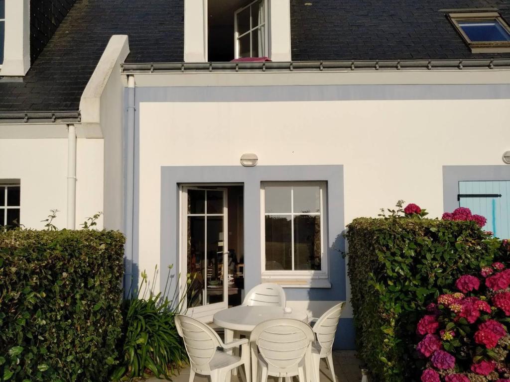 une table et des chaises blanches devant une maison blanche dans l'établissement Maison avec piscine et terrasse proche plage - FR-1-418-254, à Locmaria