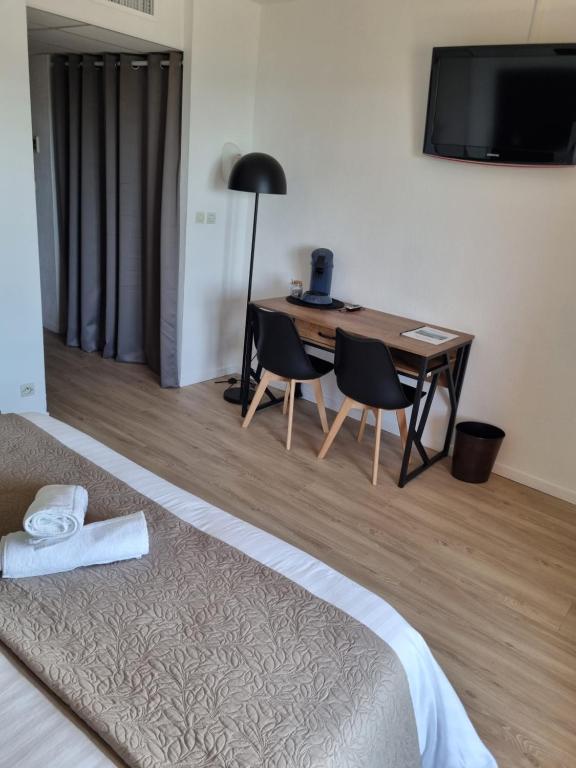 a bedroom with a desk with two chairs and a television at Auberge des Salles in Les Salles-sur-Verdon