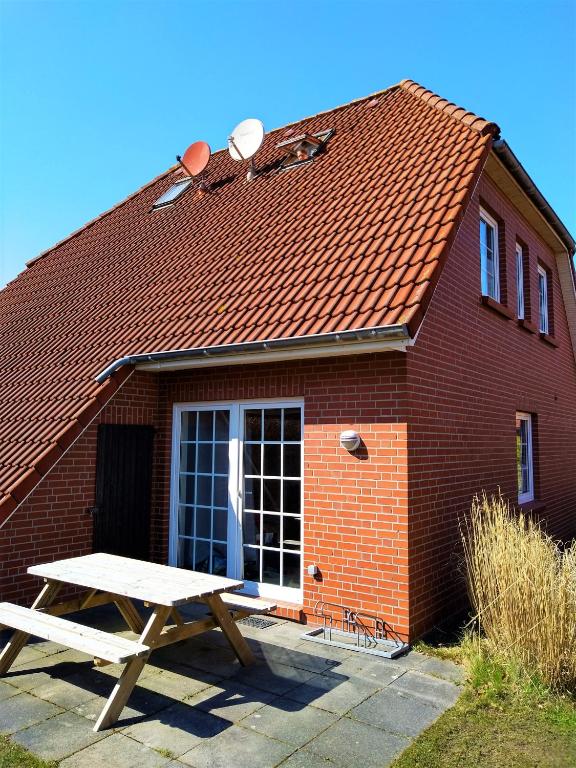 a picnic table in front of a brick building at Ferienhaus Kolibri, exklusiv und familiär in Neßmersiel mit Anbindung nach Baltrum in Neßmersiel