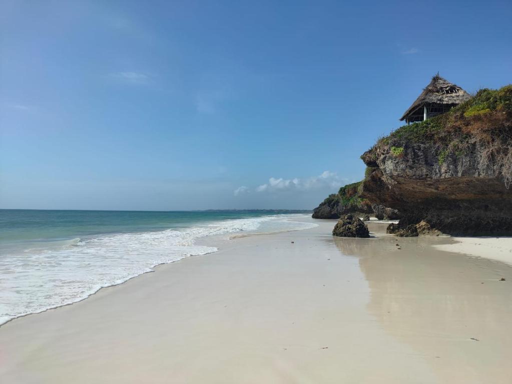 a beach with a house on top of a cliff at Malaica in Kilifi