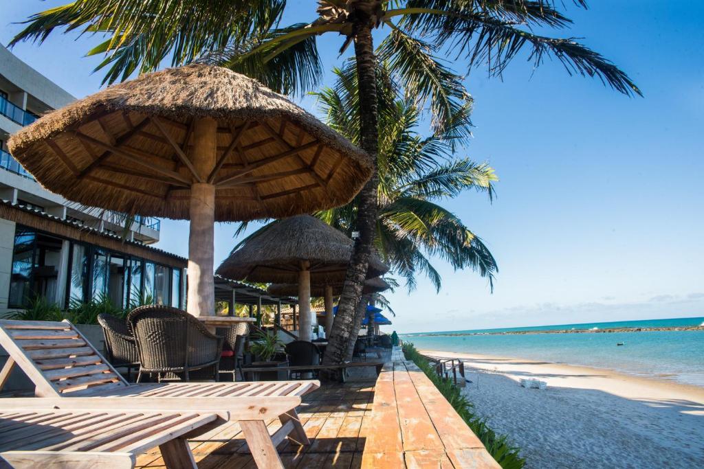 a beach with chairs and umbrellas and the ocean at Village Barra Hotel in Barra de São Miguel