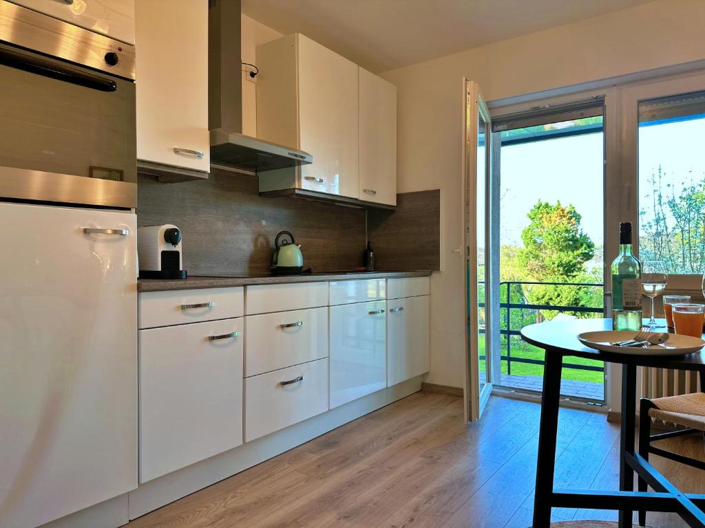 Essen的住宿－Garten-Blick-Baldeneysee，厨房配有白色橱柜、桌子和窗户。