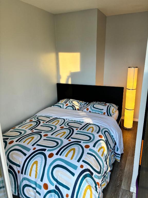 - un lit avec une couette colorée dans une chambre dans l'établissement Appartement Cosy proche Paris La Défense, à Sartrouville