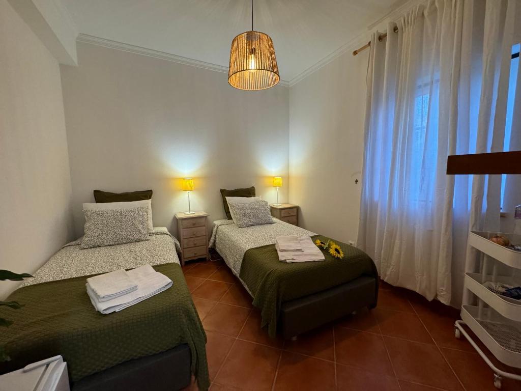 a bedroom with two beds and a chandelier at Casa de Praia em Almograve - Quarto trilho dos Pescadores in Odemira