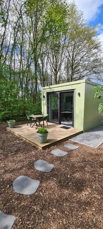 een groen tiny house met een picknicktafel op een dek bij Logies Prinsewyk De Knipe/Oranjewoud 
