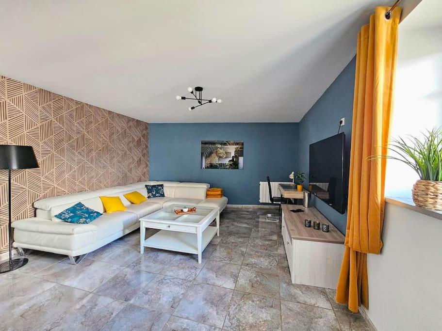 een woonkamer met een witte bank en een tv bij Gîte Le Jaguar in Custines