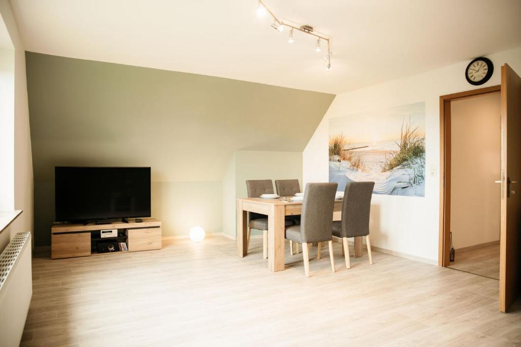 a dining room with a table and chairs and a television at Ferienwohnung Hohner Seeblick in Hohn