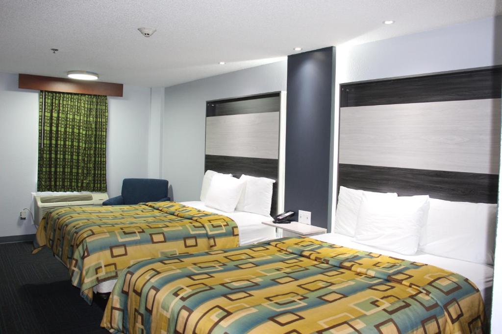 une chambre d'hôtel avec deux lits et une chaise dans l'établissement Douglas Inn & Suites, à Cleveland