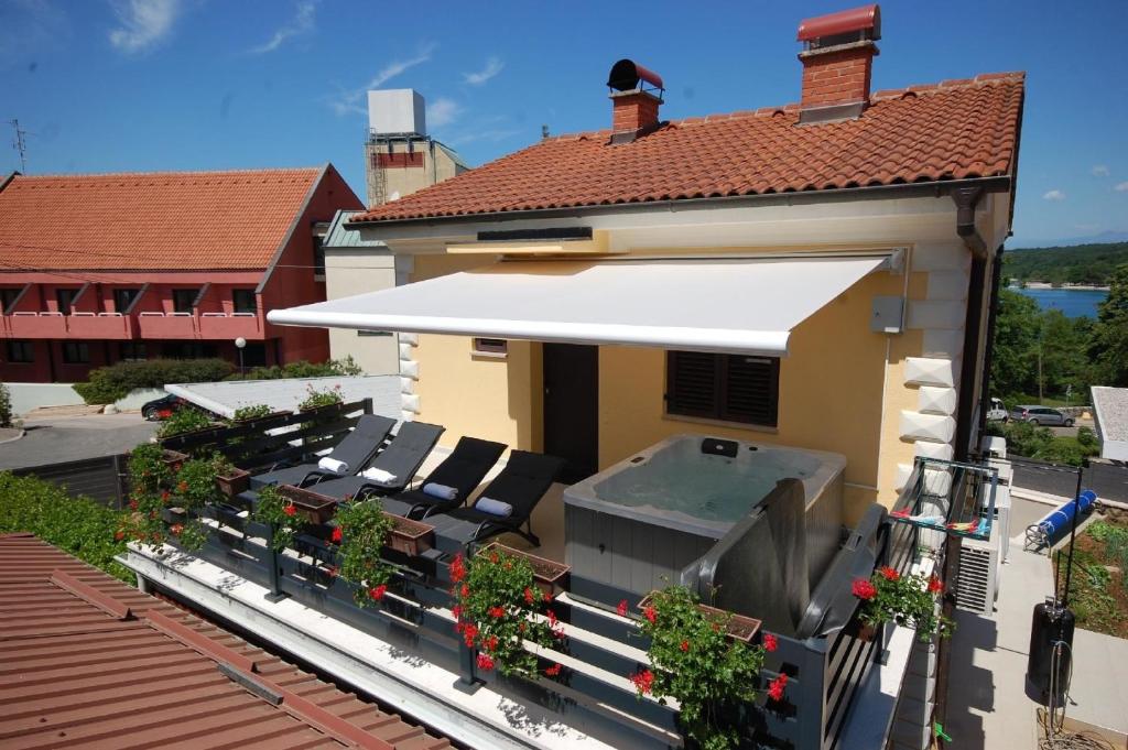 ein Haus mit einer weißen Markise auf dem Balkon in der Unterkunft Studio für 4 Personen ca 40 qm in Njivice, Kvarner Bucht Krk in Njivice