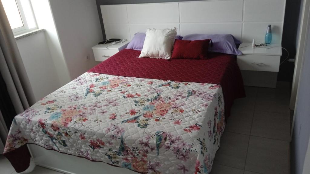 a bedroom with a bed with a quilt on it at Casa Mrichica in Mão para Trás