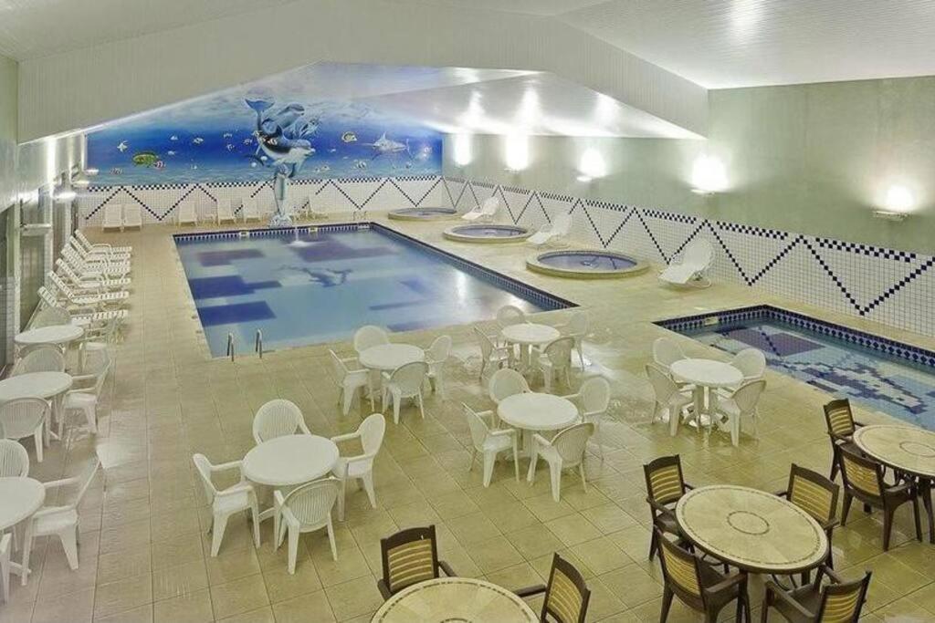 una piscina con mesas y sillas en Apartamento completo em Resort en Represa Capivari