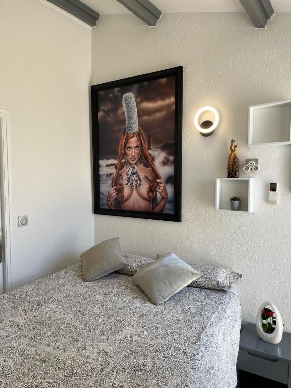 una TV appesa a un muro sopra un letto di BEGOOD'IZ naturiste Studio indépendant au calme au coeur du village a Cap d'Agde