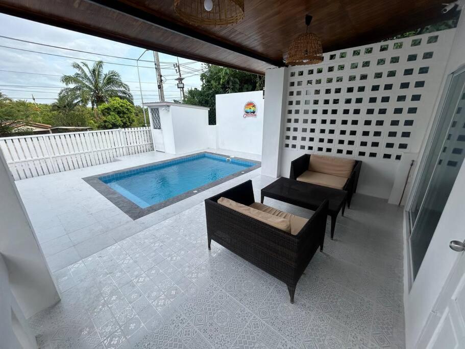 a patio with a swimming pool and two chairs and a table at Pool villa copacolanta in Ko Lanta