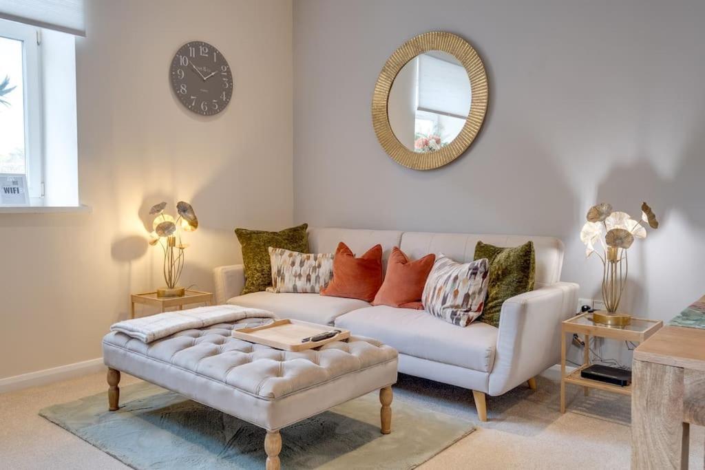 a living room with a white couch and a mirror at Stylish Modern Town Centre Flat in Carterton