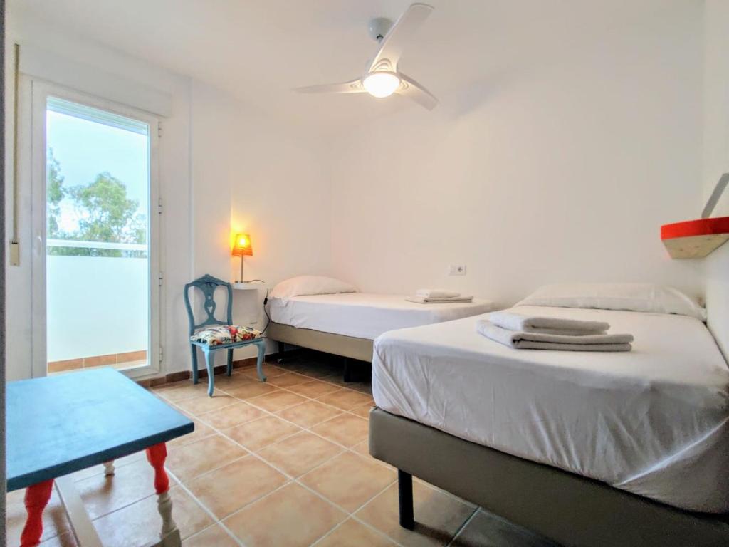 a bedroom with two beds and a table and a window at Casa Bonica in Palomares