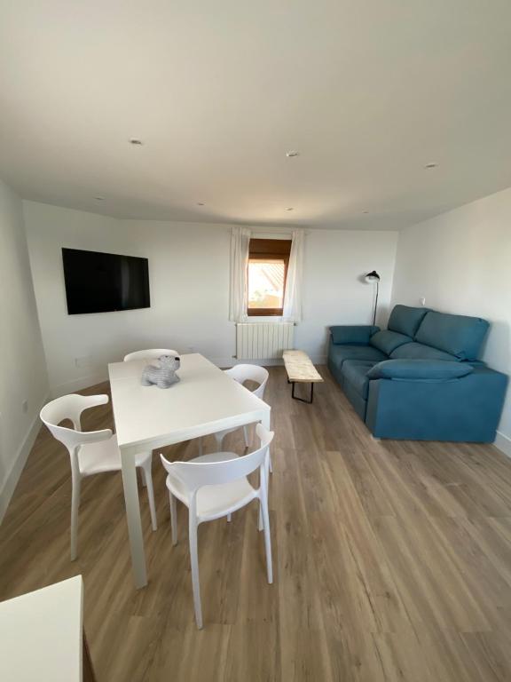 ein Wohnzimmer mit einem blauen Sofa, einem Tisch und Stühlen in der Unterkunft EL RINCÓN DE DENVER in Suances