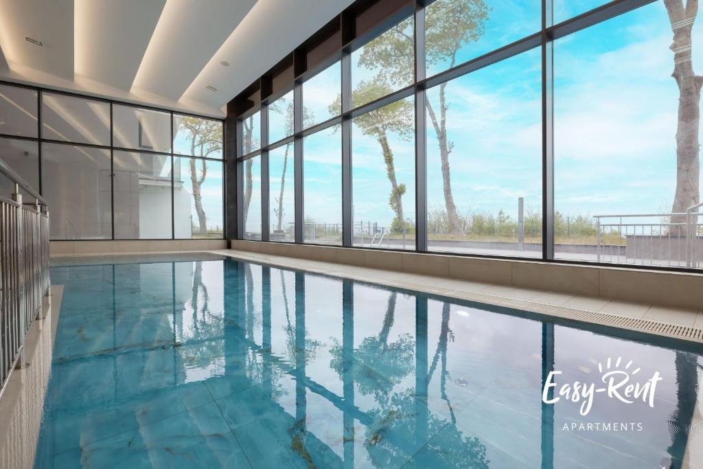 a swimming pool in a building with large windows at Blue BIEN Easy - Rent Apartments z widokiem na morze in Rewal