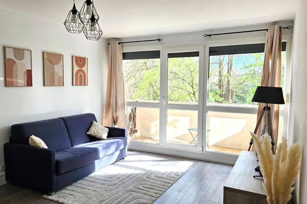 uma sala de estar com um sofá azul e uma grande janela em Agréable 2 pièces à Savigny sur Orge em Savigny-sur-Orge