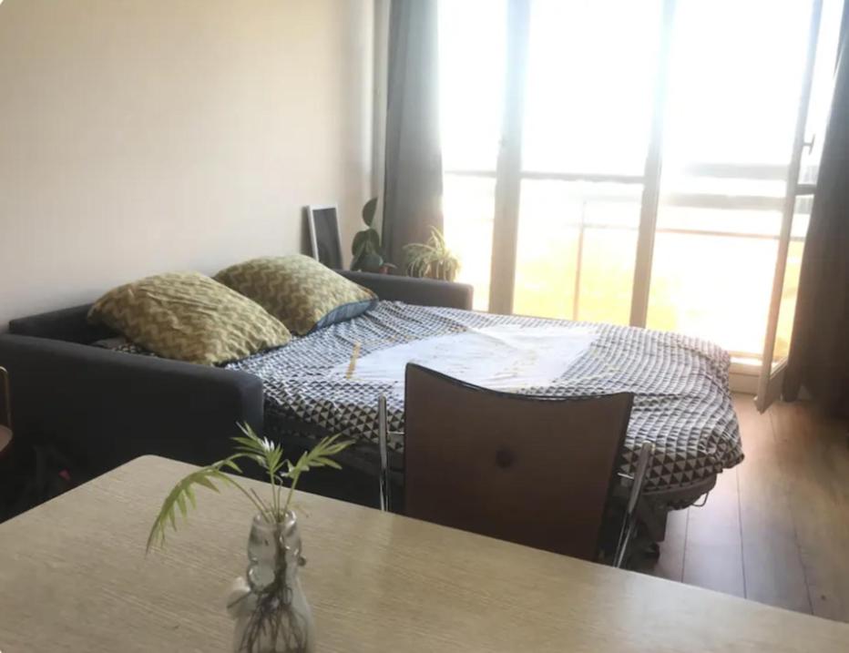 ein Schlafzimmer mit einem Bett, einem Tisch und einem Sofa in der Unterkunft Le 7eme étage in Pantin