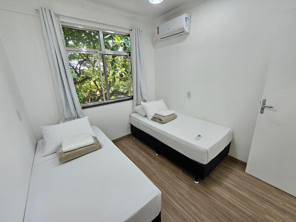 two beds in a small room with a window at Quarto Privativo em Condominio in Rio de Janeiro