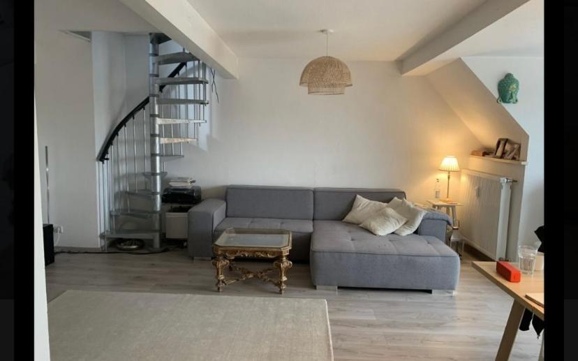 a living room with a gray couch and a staircase at Loft Düsseldorf City in Düsseldorf