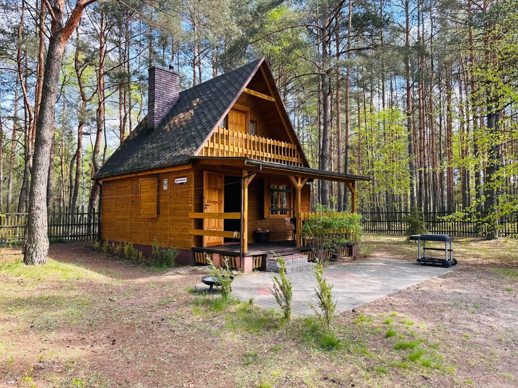 una cabaña en el bosque con una valla negra en Leśniczówka, en Rządza