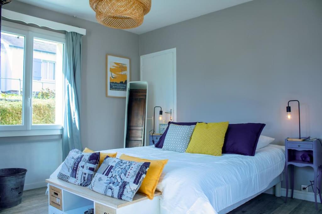 ein Schlafzimmer mit einem großen weißen Bett mit bunten Kissen in der Unterkunft Ar Mervent/Plage à pieds in Crozon