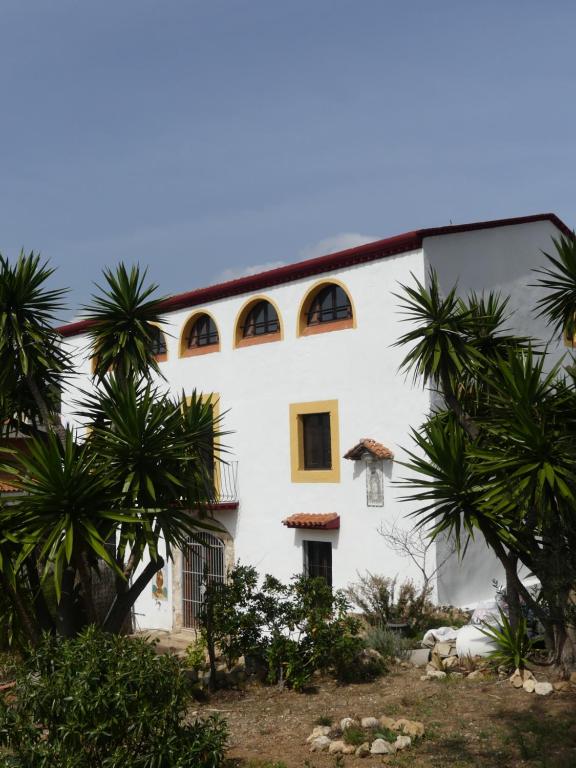 um edifício branco com palmeiras em frente em Apartamento en Masia catalogada em Tarragona