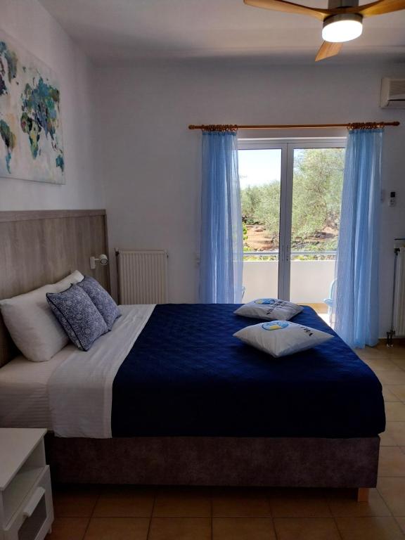 um quarto com uma cama grande com lençóis azuis e uma janela em Villa Chariklia Studios em Kambiá