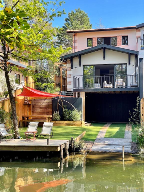 une maison avec un quai à côté d'une masse d'eau dans l'établissement Villa du Canal - Ponton pour bateau, à Cazaux