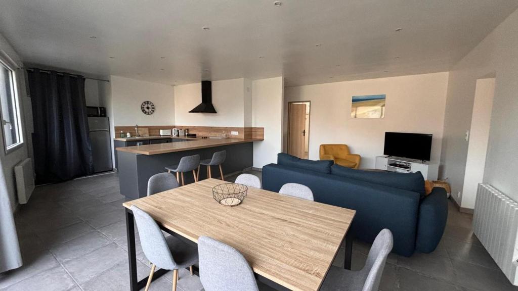 a living room with a blue couch and a table at Bel appartement à 200m de la plage in Barneville-Carteret