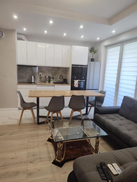 a living room with a table and chairs and a kitchen at Apartament Klimatyzowany na Ciepłej in Białystok