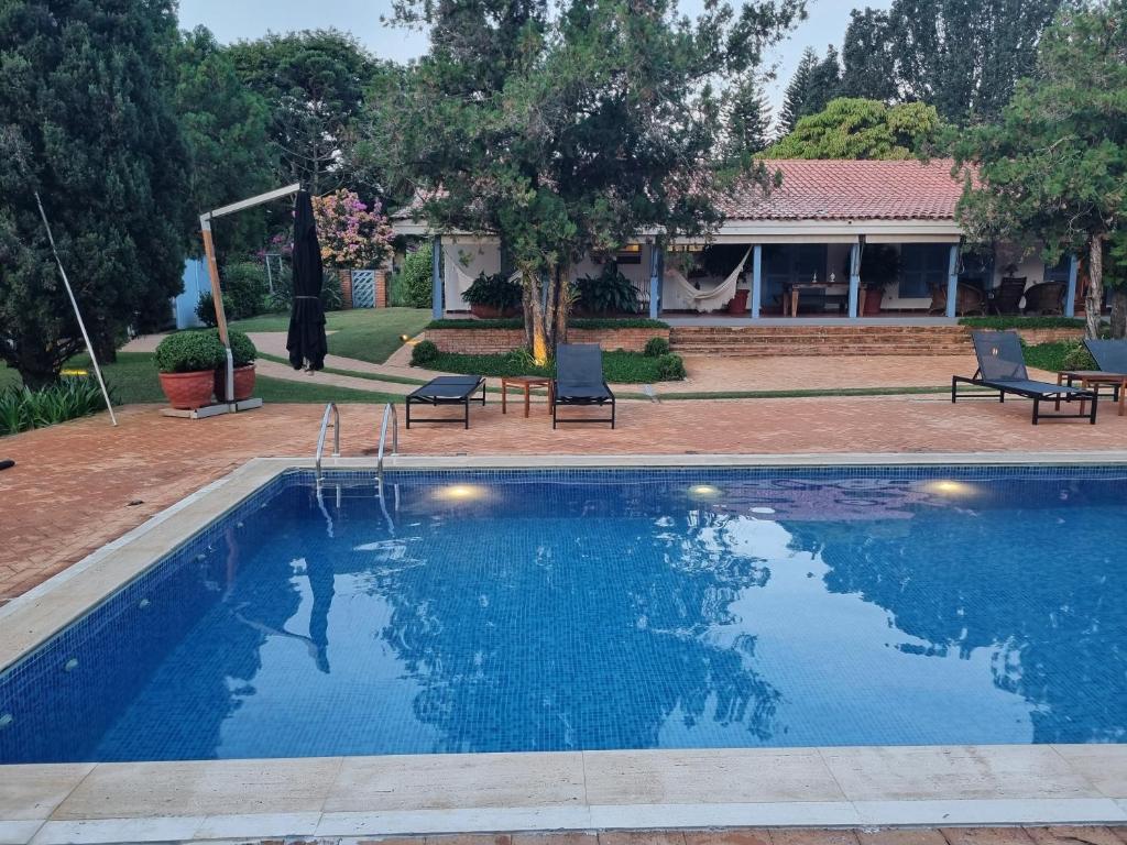 een zwembad met twee stoelen en een huis bij Casa no Condomínio Vila Pinhal na represa do Broa. in Itirapina