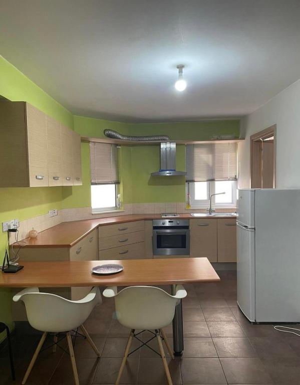 a kitchen with a wooden table and a refrigerator at Lovely studio in Makedonitissa in Nicosia