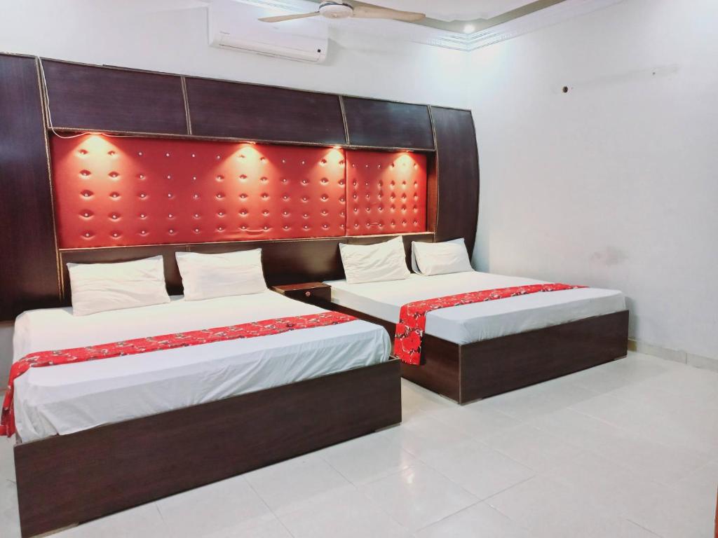 a bedroom with two beds with red headboards at Rose Palace Guest House in Karachi