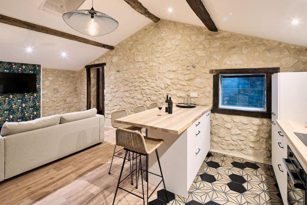 een keuken en een woonkamer met een stenen muur bij Gîte au cœur des vignes in Montagne